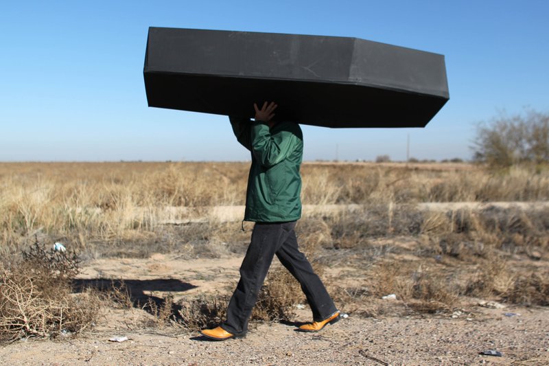 A demonstrator carries a mock coffin, representing migrants who have died, outside the U.S. Immigration and Customs Enforcement detention center in Eloy, Ariz.  