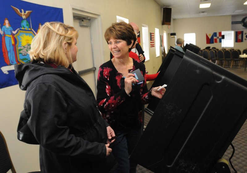 Tamara Beard (left) votes Tuesday March 1, 2016 with assistance from Linda Elsner, poll worker, at Colonial Baptist Church in Rogers. Poll workers reported brisk voter turnout for Tuesday's primary election.