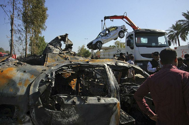 Civilians and security forces gather as workers remove destroyed vehicles at the scene of a suicide bomb attack in Hillah, Iraq, about 60 miles south of Baghdad, on Sunday.