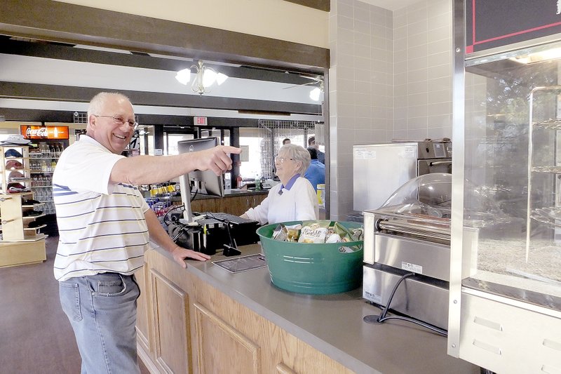 Lynn Atkins/The Weekly Vista Metfield Deli Manager Shirley Hatfield and customer Kenny Giese share a smile about the last hot dog on Metfield&#8217;s new hot dog turner. The Metfield Deli had its soft opening last week.