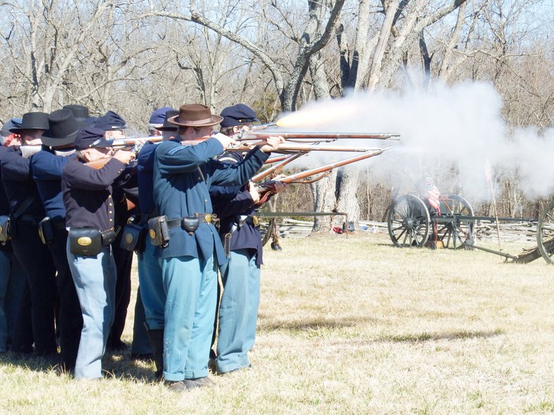 TIMES photograph by Annette Beard Fire glowed from a replica rifle as Union soldiers re-enactors of Company B, 24th Missouri, fired a volley while demonstrating infantry maneuvers during the 154th anniversary of the Battle of Pea Ridge Saturday. Reenactors set up camps and demonstrated rifle and cannon fire throughout the day in the fields at Elkhorn Tavern, Pea Ridge National Military Park, Garfield.