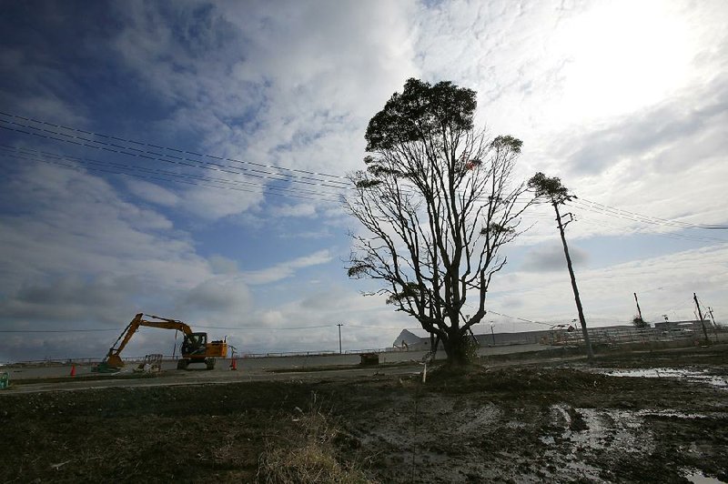 A worker uses a power shovel to remove the contaminated topsoil in Tomioka, Fukushima Prefecture, northeastern Japan in February.