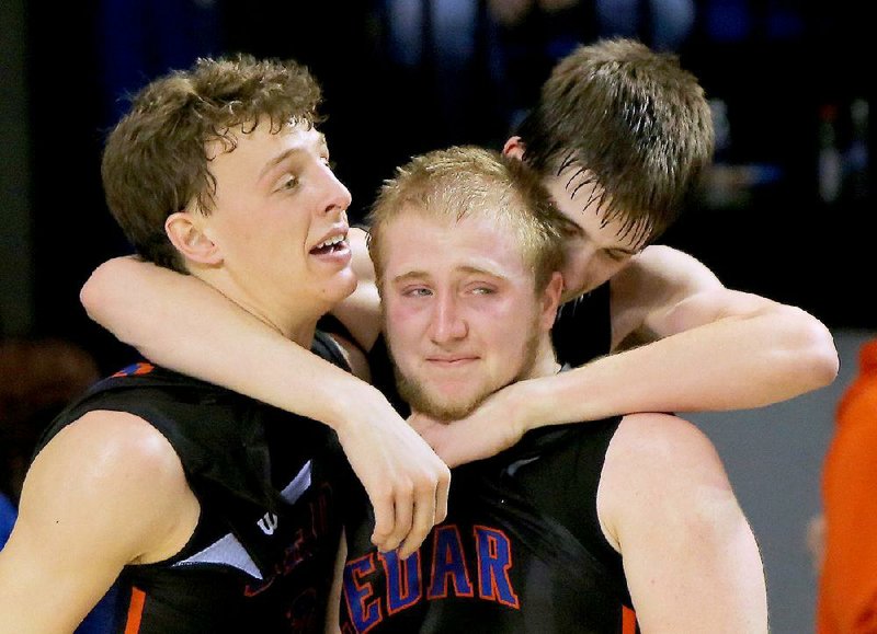 Cedar Ridge’s Cade Crabtree (left) and Keagan Harrison (center) get a hug from teammate Austin Reaves as time runs out in their 75-60 victory over Charleston in the Class 3A boys state championship game at Bank of the Ozarks Arena in Hot Springs.