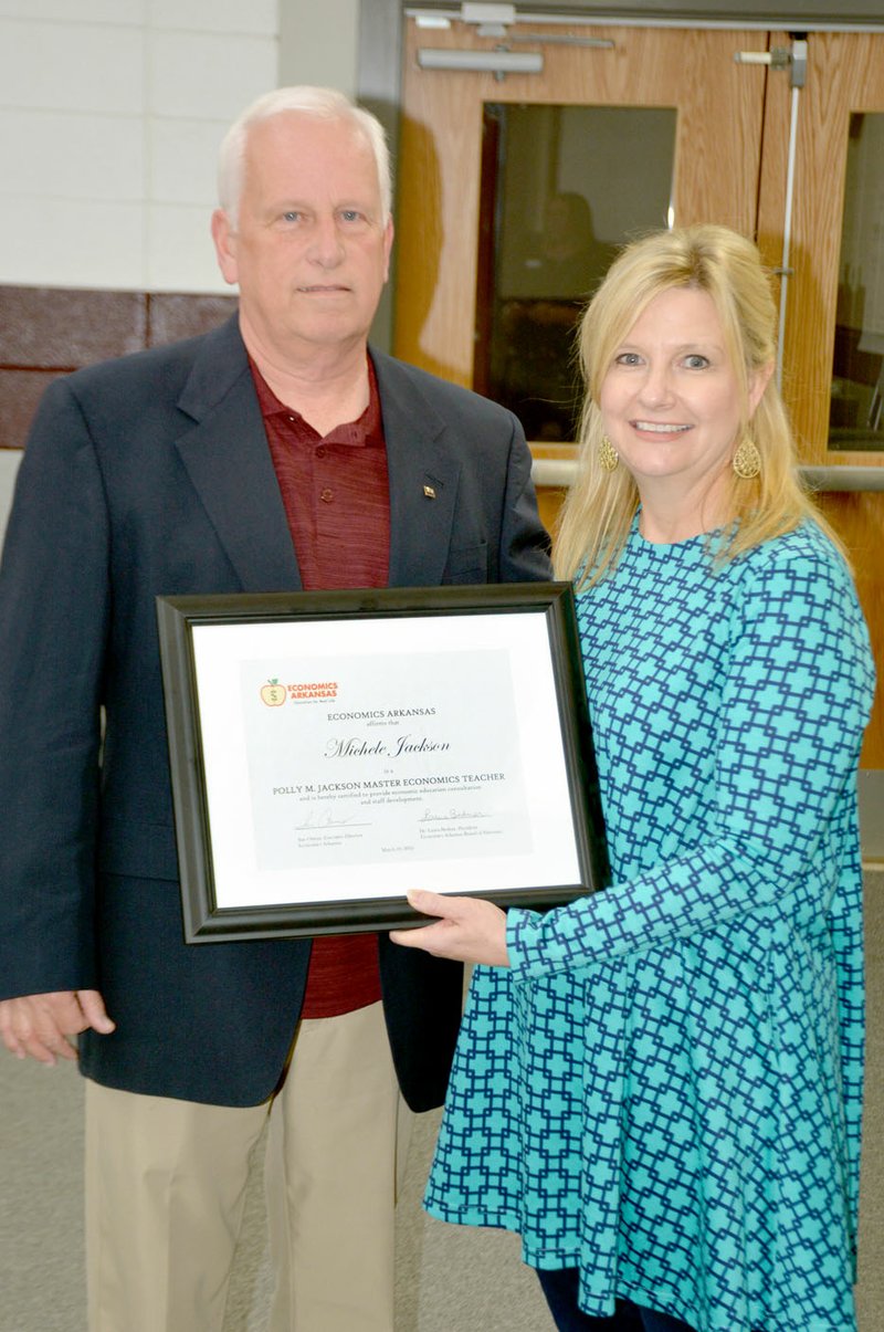 Janelle Jessen/Herald-Leader Ray Hobbs, Economics Arkansas board member, presented teacher Michele Jackson with a certificate naming her a Polly M. Jackson Master Economics Teacher during Thursday&#8217;s school board meeting. Economics Arkansas certifies outstanding economics educators as Master Economics Teachers, according to the organization&#8217;s website. Participants in this choice initiative serve as &#x201c;resource extenders&#x201d; by providing training in economics and personal finance to other teachers across the state. Candidates undergo a rigorous nomination, selection and testing process before certification, the website states. Jackson is a previous winner of the Economics Arkansas Bessie B. Moore award.