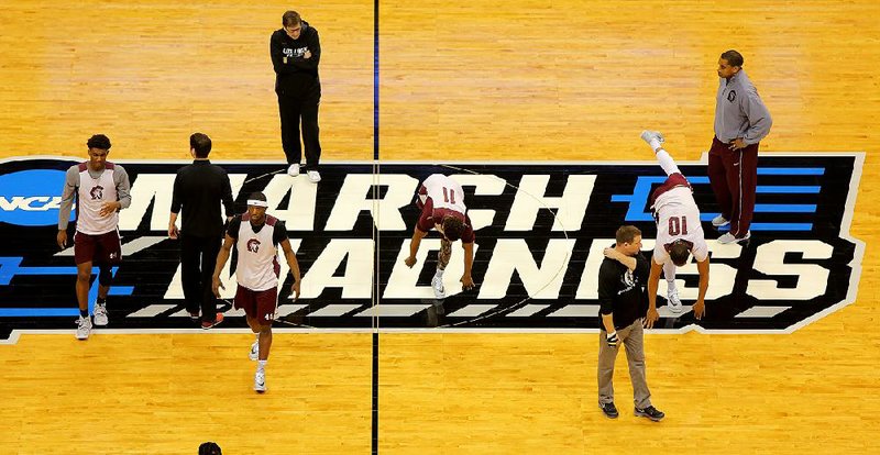 UALR coaches and trainers watch as Trojans players warm up before Wednesday’s practice session at the Pepsi Center in Denver. UALR, a No. 12 seed, takes on No. 5 seed Purdue today in the first round of the NCAA Tournament.