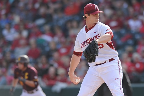 Starter Dominic Taccolini of Arkansas delivers a pitch as Jason Sullivan of Central Michigan leads off of first base Friday, Feb. 19, 2016, during the first inning at Baum Stadium in Fayetteville.