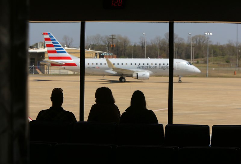 Passengers wait in the gate area of Bill and Hillary Clinton National Airport as an American Eagle plane taxis to its gate.