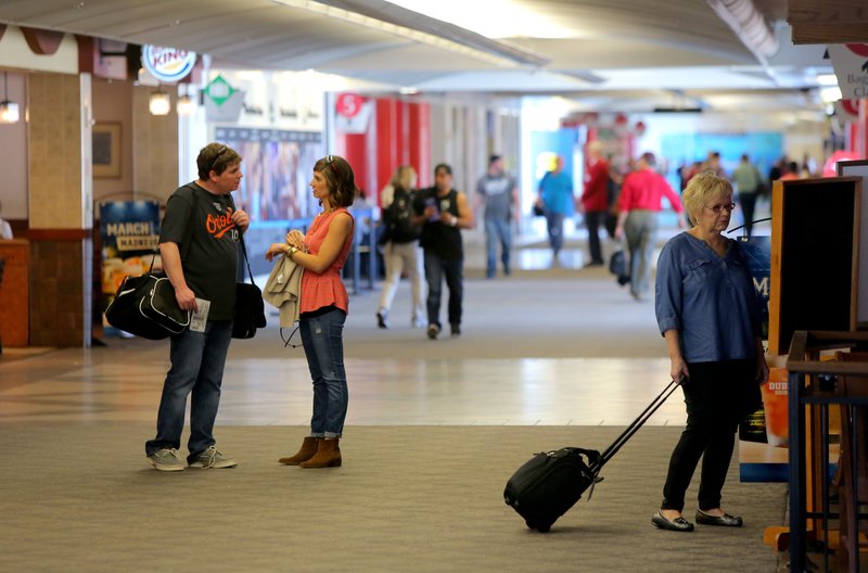 Aaron and Emily Dunn of Fayetteville check their time on the way to the gate at Bill and Hillary Clinton National Airport recently. Fewer nonstop flights are available at the airport due to mergers and consolidations.