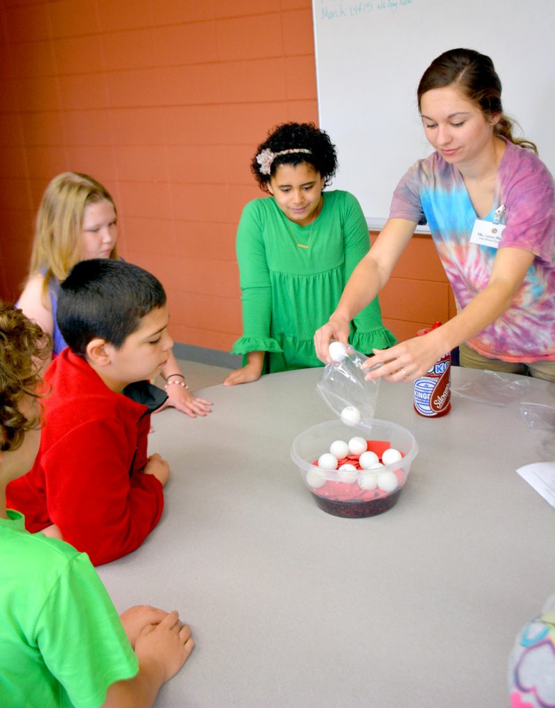 Janelle Jessen/Herald-Leader Lauren Martin, a teaching student at John Brown University, dumped ping pong balls into a bowl of water to represent white blood cells as a group of third- and fourth-grade students from Southside Elementary School looked on. Martin and her partner Brooke Williams were leading a science activity designed to teach students about the different components of blood.