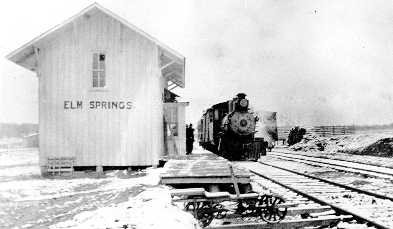 Elm Springs boasted its own railroad depot, pictured here, c. 1910s. In 1914, John Felker of Rogers built the Kansas City and Memphis Railroad — complete with depot — from Cave Springs to Elm Springs to Fayetteville. This branch railroad connected with the Kansas City Southern Railroad out of Siloam Springs to carry fruit to market. The railroad service was discontinued in 1918.