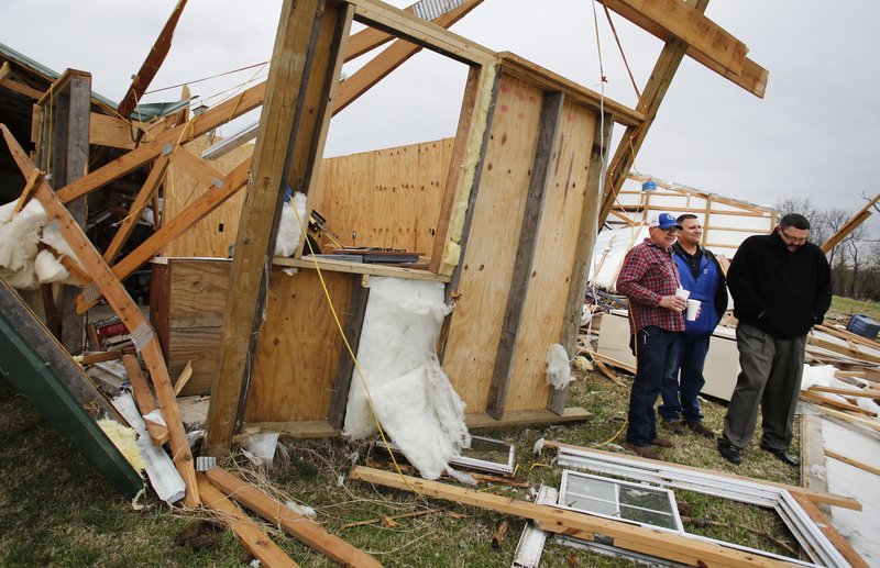 Terry Hudson (from left) stands in the debris from his work shop with friends Bill Grady an James Carey Thursday, March 24, 2016 after they came to check on him and his wife Susan on their property on Ray Road near Evansville.