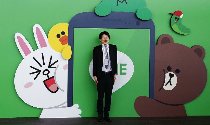 A fan poses for a photo in front of the Line Corp. logo featuring the company’s popular animal characters.