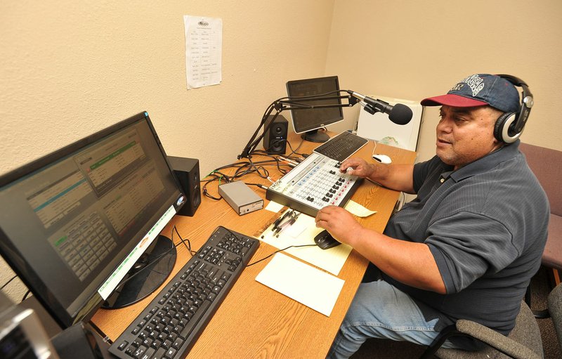 Larry Muller, manager of KMRW 98.9 FM, a low-power Marshallese radio station in Springdale, checks the music playing Friday in Springdale.