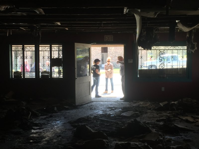 Annette Jones, center, stands with family viewing the gutted interior of her restaurant, Three Sam's BBQ Joint, after it was destroyed in a fire Monday. 