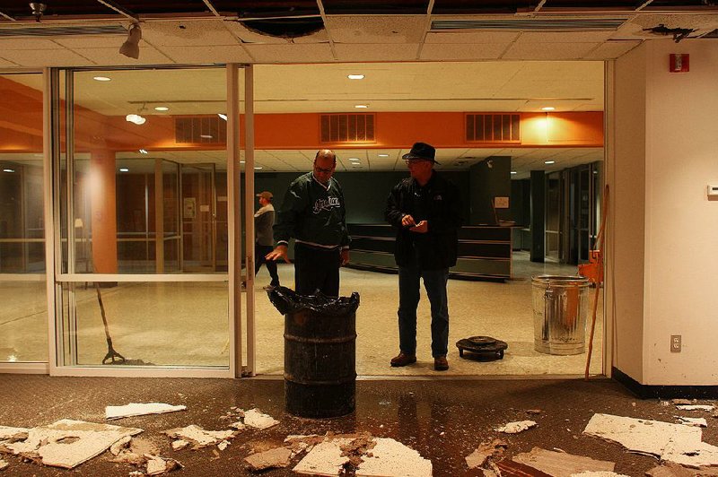 Todd Herman, with the Arkansas Arts Center, describes damage to Mike Flowers, with Arkansas Mold and Water Inc., at the entrance to the center’s Lecture Hall on Wednesday night. Water broke through the drop ceiling tiles during a heavy rainstorm but the damage was contained to the west wing and none of the center’s art collection was affected. 
