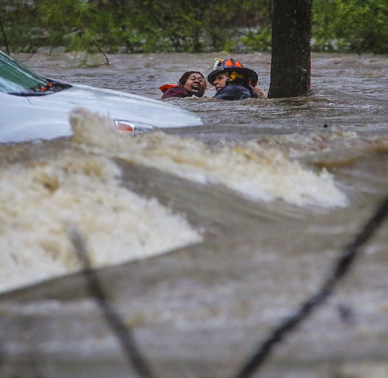 Little Rock Fire Capt. Steve Kotch rescues an unidentified woman whose car was caught in 
flooding Wednesday afternoon in Boyle Park. Though attached to a safety line, Kotch and the woman were knocked off their feet at least twice. Storms dumped heavy rain on parts of the state, prompting several rescues, damaging a major North Little Rock roadway and sending water pouring into a section of the Arkansas Arts Center in Little Rock. 