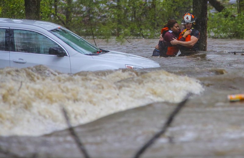 Little Rock Fire Capt. Steve Kotch (right) grips an unidentified woman as he rescues her from her flooded car in Little Rock’s Boyle Park during Wednesday afternoon’s heavy rainfall. Kotch and the woman were on a cable safety line but it appeared as though the woman, in panic, pulled the two off their feet at least twice during the rescue.
