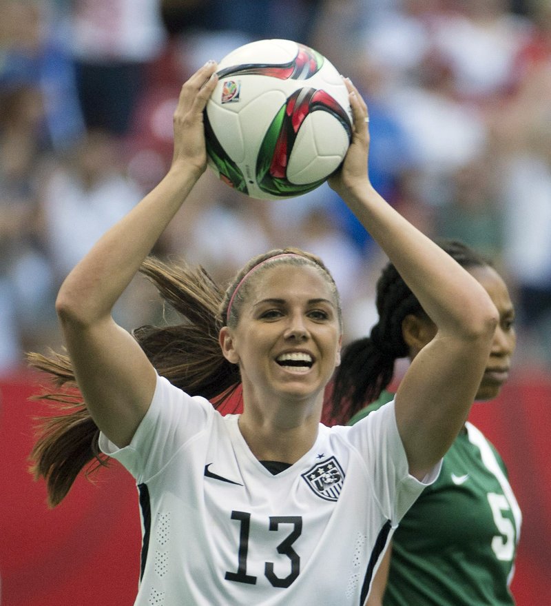 In this June 16, 2015, file photo, United States' Alex Morgan celebrates teammate Abby Wambach's goal as Nigeria's Onome Ebi looks on during the first half of a FIFA Women's World Cup soccer match in Vancouver, British Columbia, Canada. Five players from the World Cup-winning U.S. national team have accused the U.S. Soccer Federation of wage discrimination in an action filed with the Equal Employment Opportunity Commission. 