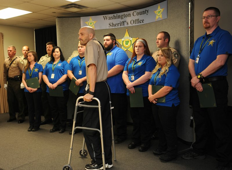 Lt. Tion Augustine (center) smiles Thursday as he stands during a ceremony with all of the members of the Washington County Sheriff’s Office staff involved in a call March 15 resulting in Augustine being shot at the Sheriff’s Office annex in Fayetteville.