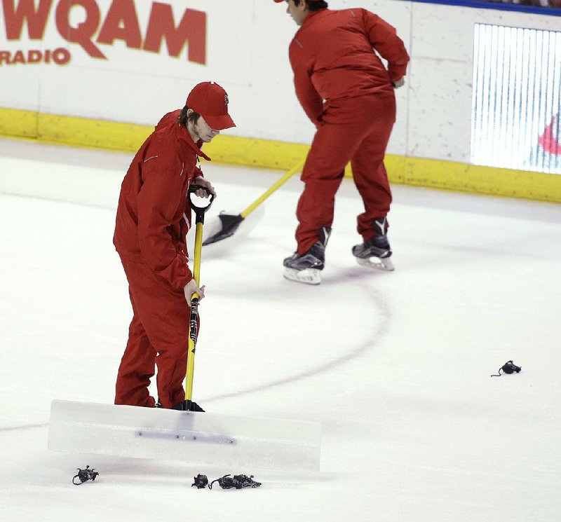 Workers scoop away toy rats thrown onto the ice by fans during the third period of the Florida Panthers’ 3-2 victory over the New Jersey Devils on Thursday. The Panthers were penalized twice because fans disregarded warnings not to throw the team giveaways onto the ice.
