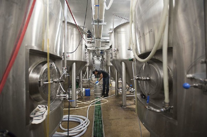 Jorge Lopez works on storage vessels at Core Brewing and Distilling Co. in Springdale.