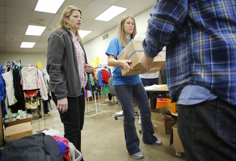 Melissa Rogers (left) and Sara Blickenstaff, both social workers for Fayetteville Public Schools, distribute a box of food and hygiene products Friday at The Outback in Building G on the Agee-Lierty Life Preparation Services center campus in Fayetteville. The food pantry is open Friday and distributes food to families with students in Fayetteville Public Schools. The Outback can distribute clothing for students through a partnership with the Potter’s House Thrift Store.