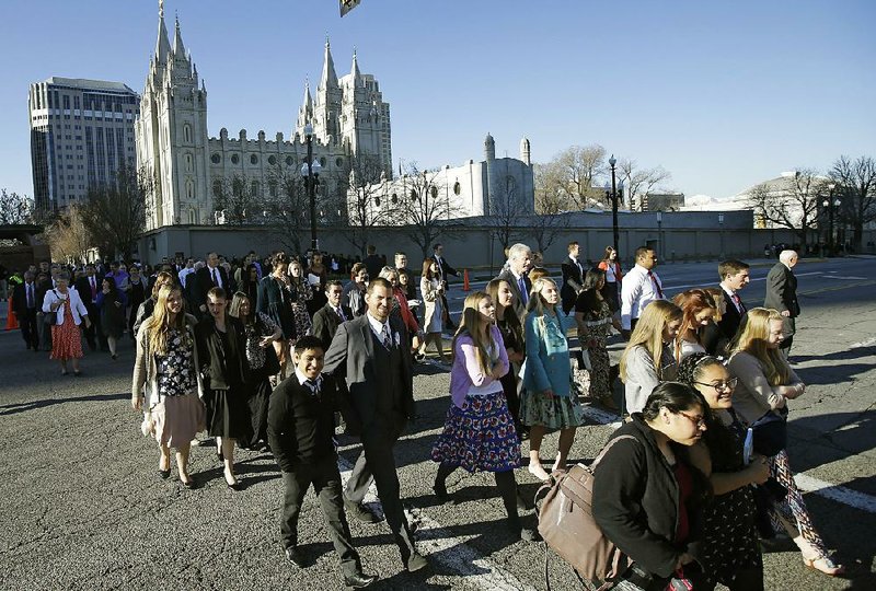 People walk Saturday near the Salt Lake Temple on their way to the opening session of the General Conference of The Church of Jesus Christ of Latter-day Saints in Salt Lake City. 