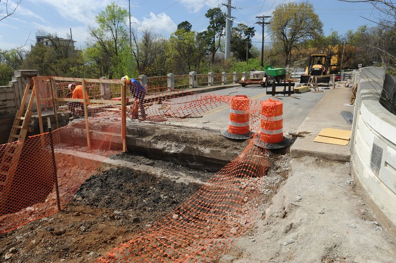 Contractors work Thursday to restore the historic Lafayette Street bridge near Dickson Street in Fayetteville. After the work is finished, the Maple Street bridge a block away will get some attention. 
