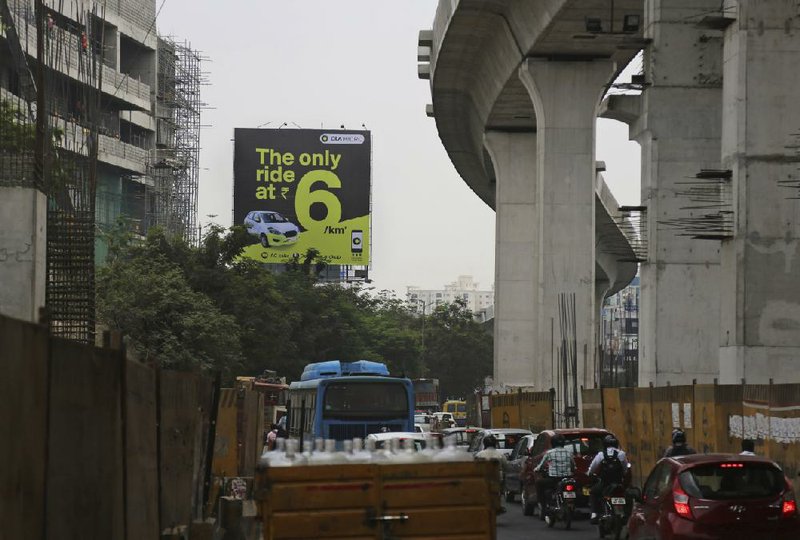 Indian commuters drive past a cluster of Ola cabs in Hyderabad, India, last week.