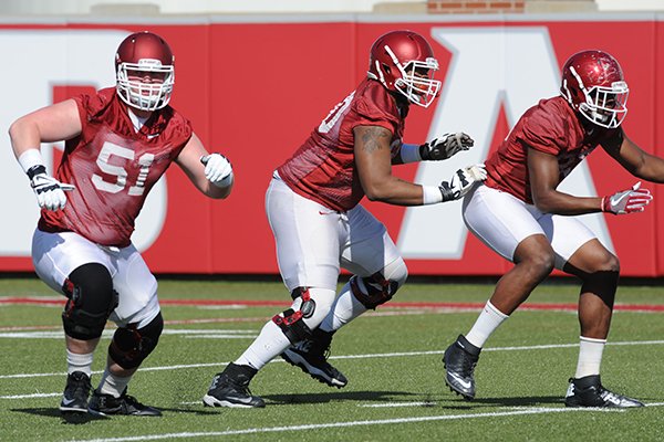 Arkansas offensive lineman Brian Wallace (center) takes part in a drill Tuesday, March 29, 2016, with tight end Jeremy Sprinkle (right) and offensive lineman Hjalte Froholdt during practice at the university's practice field on campus in Fayetteville.