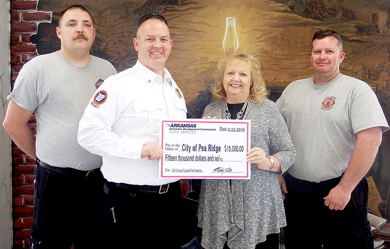 TIMES photograph by Annette Beard State Representative Sue Scott presented a $15,000 check to the Pea Ridge Fire Department Fire Chief Jamie Baggett. Gairy Osburn, paramedic, and Jason Bowman, emergency medical technician, joined him.