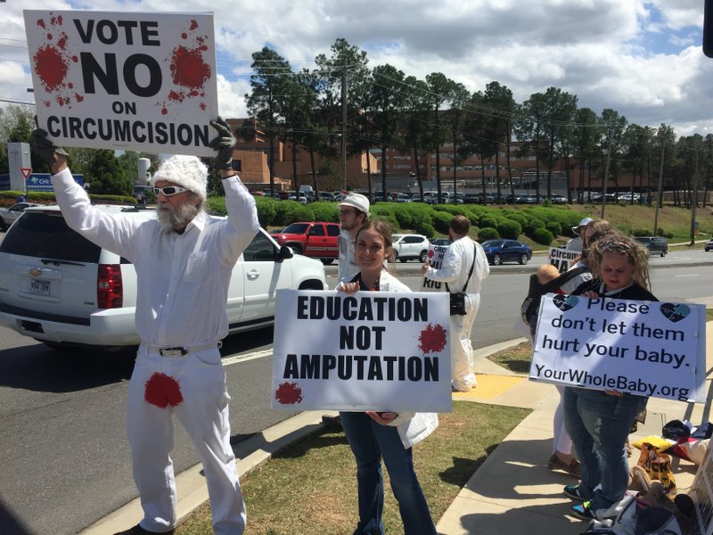 Anti-circumcision protesters hold signs at the corner of Markham Street and University Avenue, where they elicited honks and jeers from passing traffic Wednesday afternoon. 