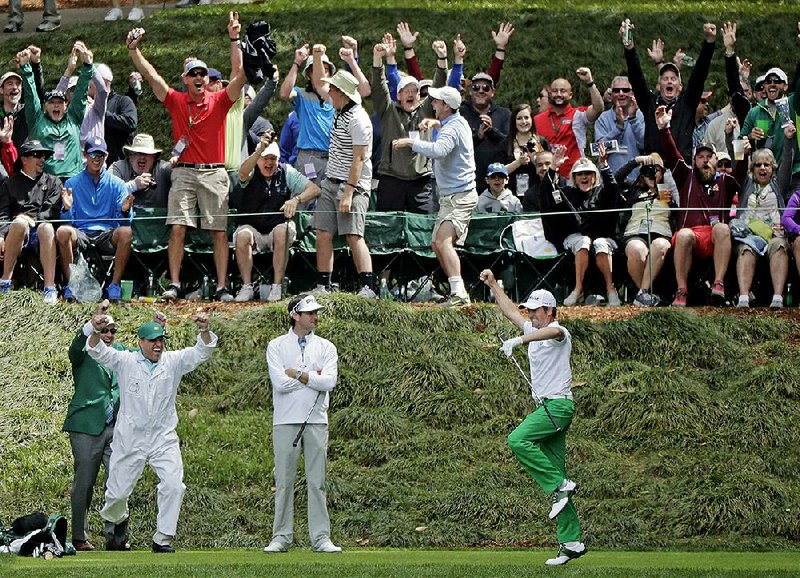 Webb Simpson (right) and his caddie celebrate Simpson’s hole in one Wednesday while Bubba Watson and the crowd look on during the Par-3 contest at the Masters in Augusta, Ga.