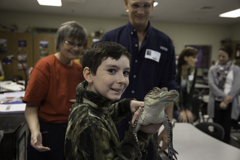 Seventh-grader Cody Galluppo holds Chomps from the Arkansas Alligator Farm and Petting Zoo in Hot Springs. Cody is a part of the Cabot Junior High School North Science Club, which raised $250 for the alligator farm after 13 gators were stolen last year. Behind him are science teacher and club sponsor Patti Benight and farm manager Jamie Bridges.