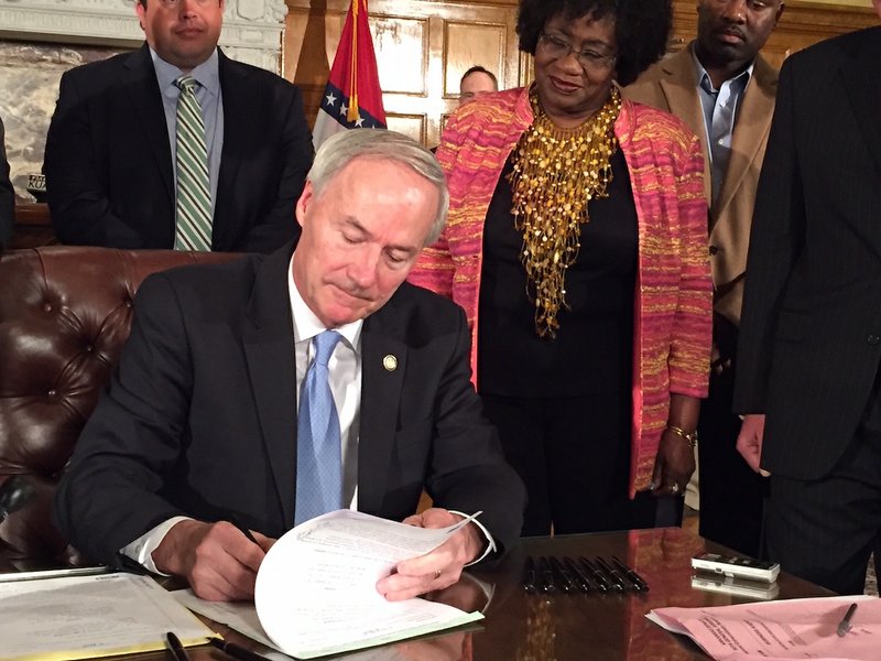 Gov. Asa Hutchinson on Friday, April 8, 2016, at the state Capitol signs into law his Arkansas Works plan, which keeps and reworks the state's hybrid Medicaid expansion. 