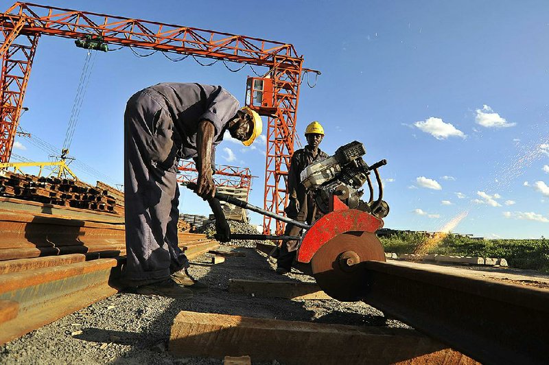 Workers slice a length of steel track for the new Mombasa-Nairobi Standard Gauge Railway at a facility in Tsavo, Kenya, in March. The new rail line is Kenya’s biggest infrastructure investment since independence in 1963. 