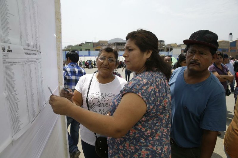 People search for their voting station number, using their IDs in San Juan de Mirafl ores shantytown during general elections Sunday in Lima, Peru.