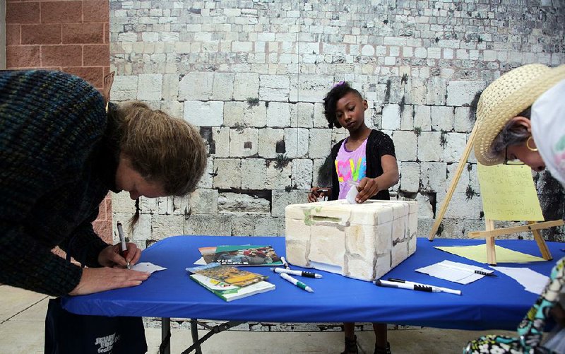 Kathleen Tanner (from left) of Little Rock, 9-year-old Madison Harper of Lonoke, and Marilyn Gillespie of Benton fill out messages to be delivered to the Western Wall in Jerusalem during the Jewish Food and Cultural Festival at War Memorial Stadium in Little Rock on Sunday.