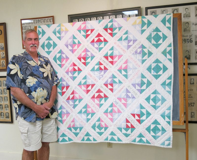 Photo by Susan Holland Steve Mitchael, chairman of the Gravette Historical Museum commission, poses beside the vintage friendship quilt recently acquired by the museum. The quilt, believed to have been made in the late 1940s, was purchased at the estate sale of Mr. and Mrs. Kenneth Skaggs in Springdale. It was pieced by Mr. Skaggs&#8217; mother and contains the names of several area residents.