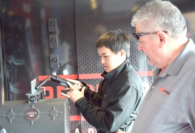 Photo by Mike Eckels Ger Xiong (center) tries his hand at the welding test station as Scott Calloway, a guide, looks on. Xiong and Calloway were part of the &#8220;Be Pro Be Proud&#8221; interactive traveling exhibit which was on display in the student parking area at Gentry High School April 7.