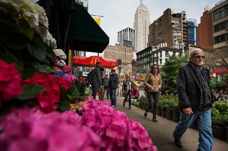 Pedestrians pass plants displayed for sale in Manhattan’s flower district in New York in last month. Sales at U.S. retailers fell 0.3 percent in March, the Commerce Department said Wednesday. 