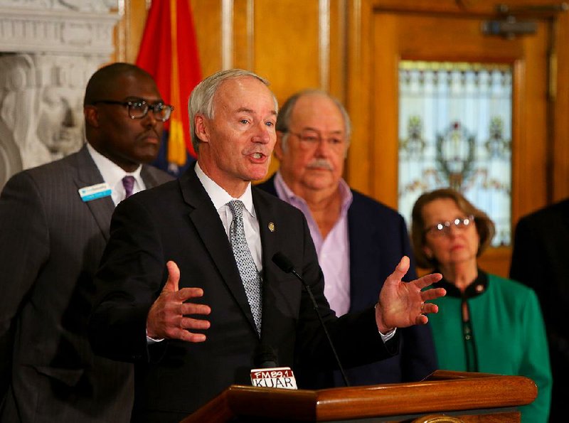 Arkansas Gov Asa Hutchinson talks at a news conference Tuesday, March 12, at the State Capitol. Behind him are State Highway Commissioner Frank D. Scott, Jr., left, commission vice chairman Tom Schueck, center and Rep. Mary "Prissy" Hickerson, R- Texarkana, right.