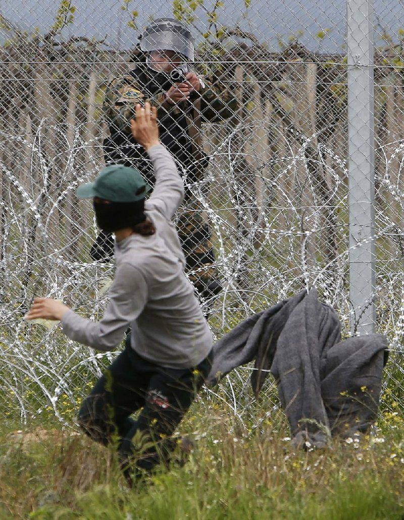 Macedonian police confront a migrant who was trying to remove razor wire from a fence at the border at Idomeni, Greece, on Wednesday. Dozens of migrants clashed with Macedonian police at the closed crossing. 