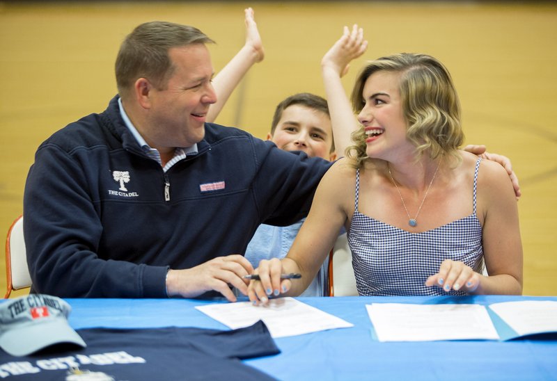 Jordan Neeley is congratulated by her father, Chris Neeley, and brother, Tucker Neeley, 11, after signing her letter of intent Wednesday at Gravette High School to run for The Citadel.