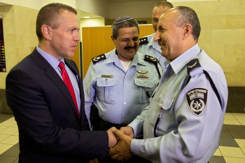 Israeli Public Security Minister, Gilad Erdan, left, shakes hands with Israeli newly-named police Deputy Commissioner Gamal Hakroosh, as Israel Police Chief Roni Alsheikh, center, looks on prior to a ceremony in Tel Aviv, Israel, Wednesday, April 13, 2016. 