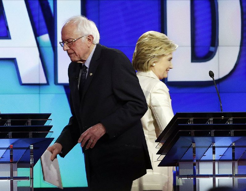 Bernie Sanders and Hillary Clinton pass each other at the start of a break in their debate Thursday night at the Brooklyn Navy Yard.