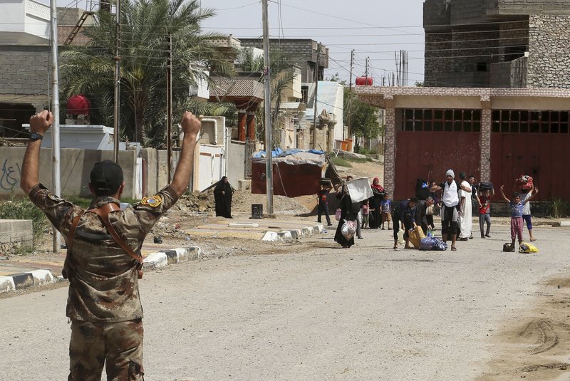 An Iraqi soldier instructs displaced people to raise their hands to check for suicide bombers during fighting between Iraqi security forces and the Islamic State group during a military operation to regain control of Hit, 85 miles (140 kilometers) west of Baghdad, Iraq, Wednesday, April 13, 2016. (AP Photo/Khalid Mohammed)