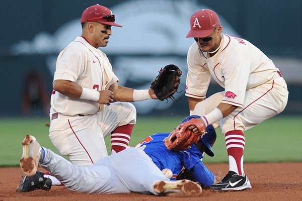 Arkansas second baseman Rick Nomura (right) loses the throw from the plate as Florida third baseman Jonathan India dives back to second Friday, April 15, 2016, as shortstop Michael Bernal backs up the play during the fourth inning at Baum Stadium in Fayetteville.