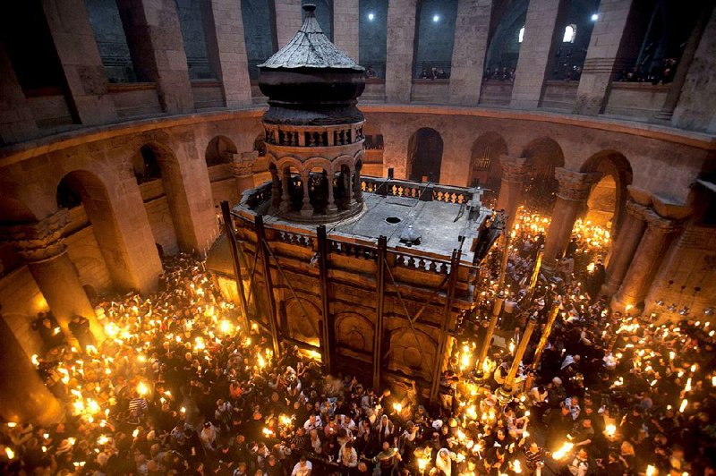 Pilgrims at the Church of the Holy Sepulcher light candles at as they stand around the Aedicule, which many Christians believe encloses the tomb of Jesus. 