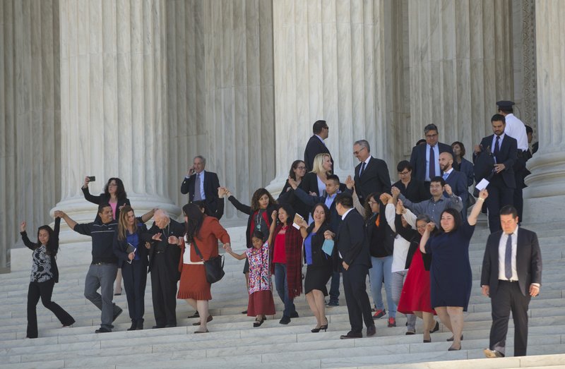 Supporters of changes to immigration policy hold hands as they leave together after listening to arguments Monday at the Supreme Court in Washington in a case that pits Texas and other states against the White House.